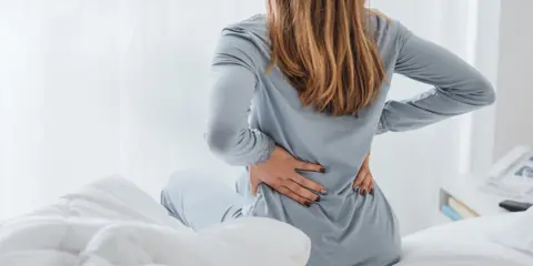 Kobieta z bólem pleców zastanawia się, czy osteoporoza jest wyleczalna.