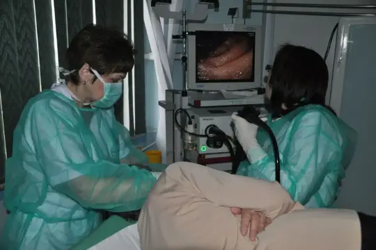 Lekarze w zielonych fartuchach obserwują obraz z wnętrza żołądka na monitorze, pokazując, jak wygląda gastroskopia.