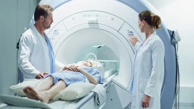Pacjentka leży w aparacie do rezonansu magnetycznego, gdzie lekarze przygotowują badanie z kontrastem.