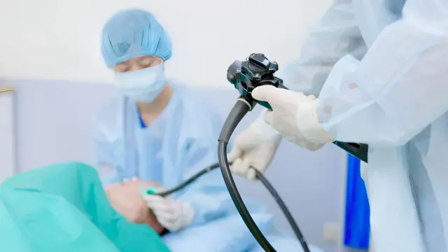 Lekarz w rękawiczkach i fartuchu przeprowadza gastroskopię, badanie pozwalające zajrzeć do żołądka.